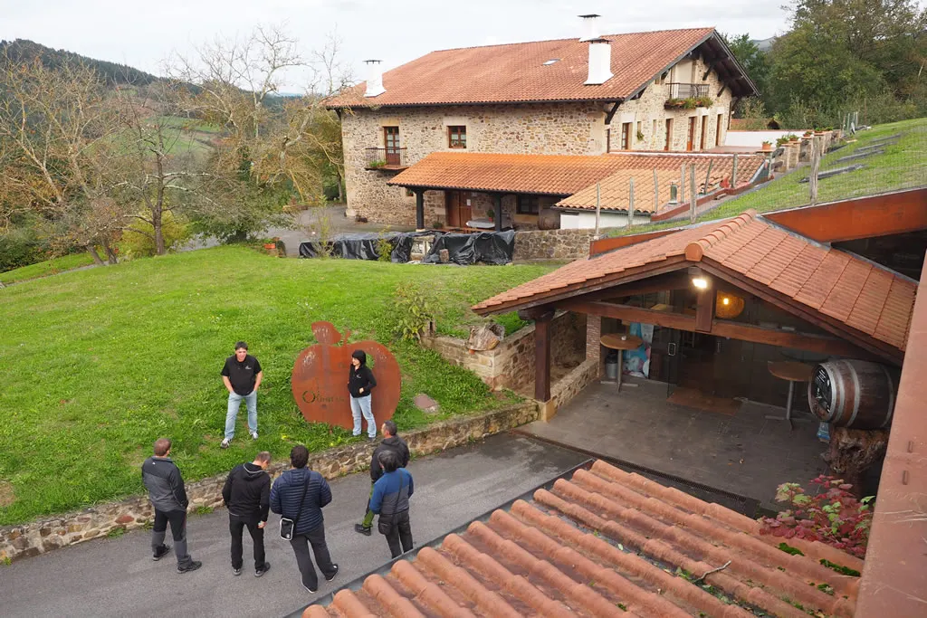 A group of visitors at the entrance to the Oiharte cellar, with the stone farmhouse behind