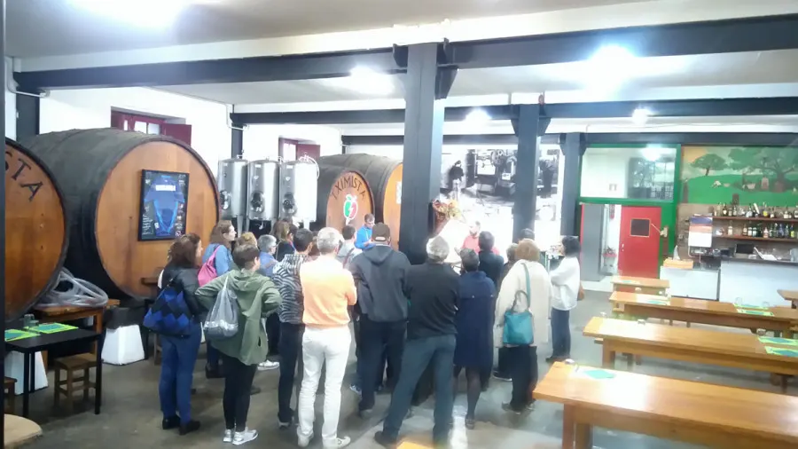 Group of visitors in the Tximista cider house, next to the kupelas (casks)