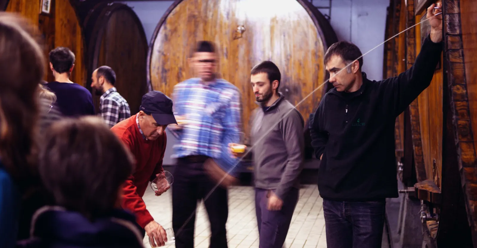 Txotx entre las grandes kupelas de madera de Barkaiztegi, con el chorro de sidra cayendo al vaso