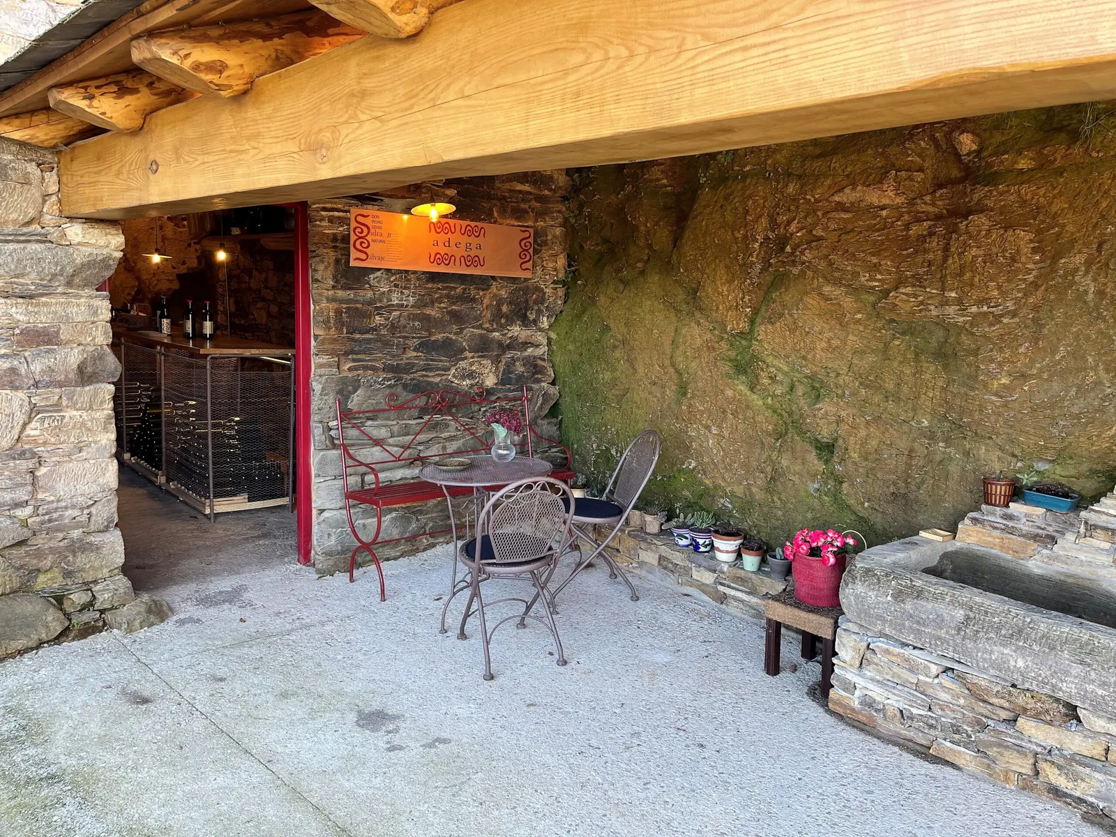 Entrada a la bodega soterrada, bajo la roca, con mesas en el exterior