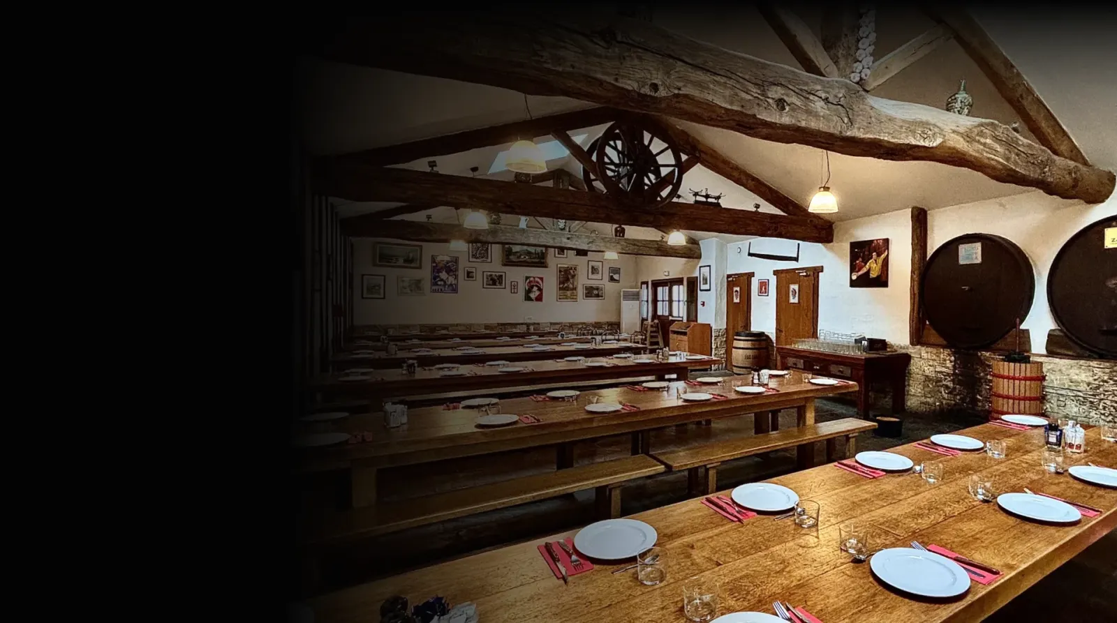 Comedor de la sidrería Du Frontón, con mesas corridas de madera puestas, vigas vistas y dos kupelas al fondo