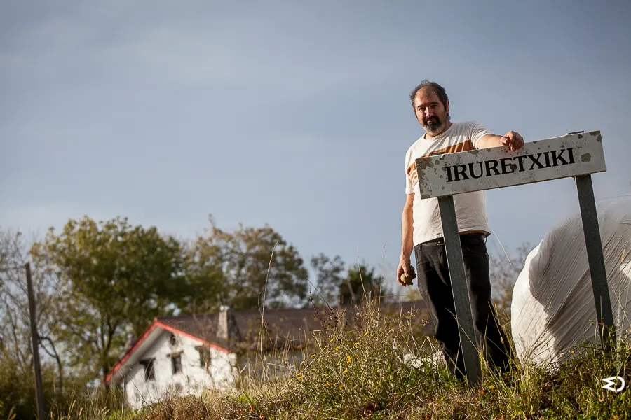 Aitor Eizmendi junto al cartel del caserío Irure Txiki, con la casa al fondo