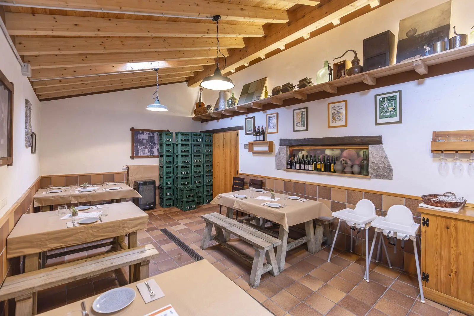 Comedor con mesas de madera, vigas en el techo y estanterías con botellas