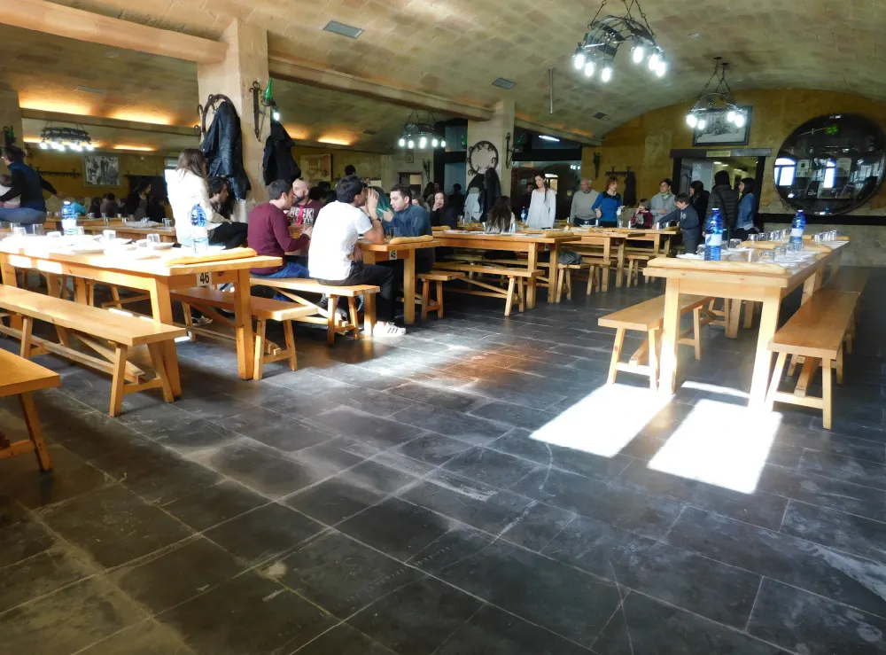 Comedor abovedado de la sidrería Etxeberria, con mesas y bancos corridos de madera y comensales