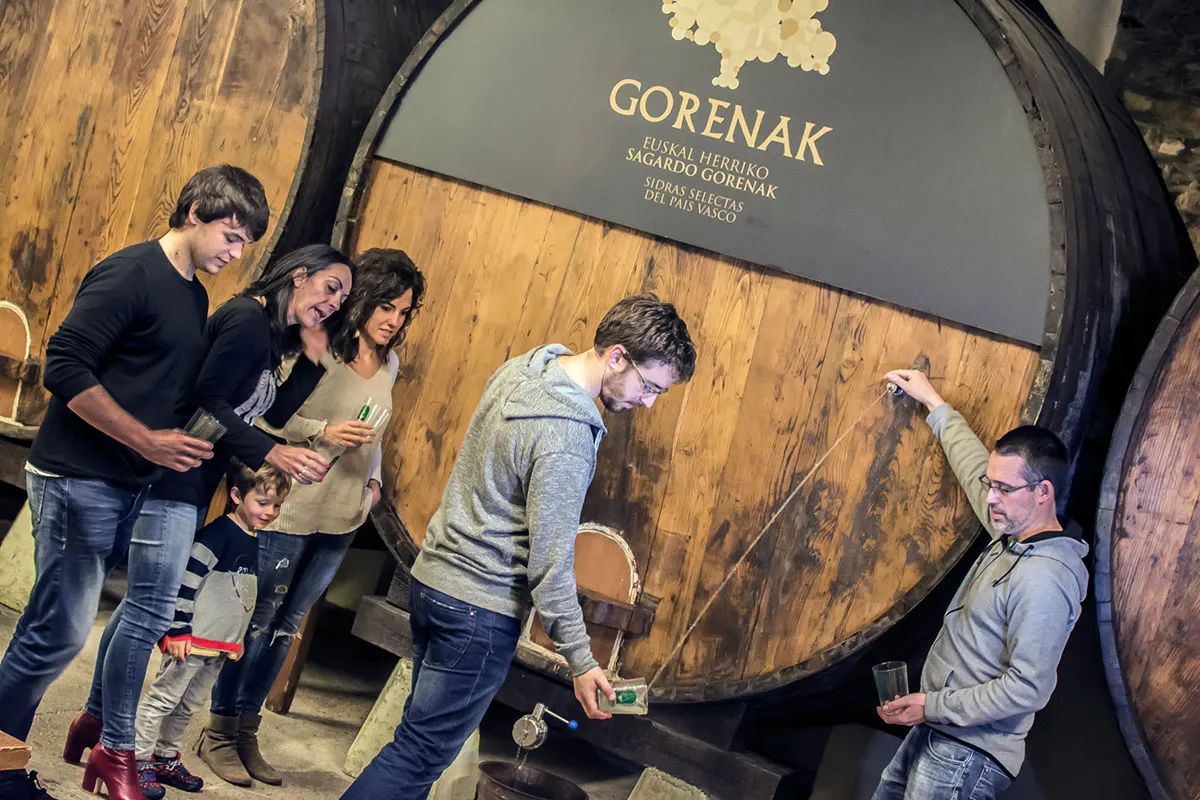 Txotx en la sidrería Isastegi, una familia recoge en el vaso la sidra de una gran kupela con el rótulo «Gorenak»