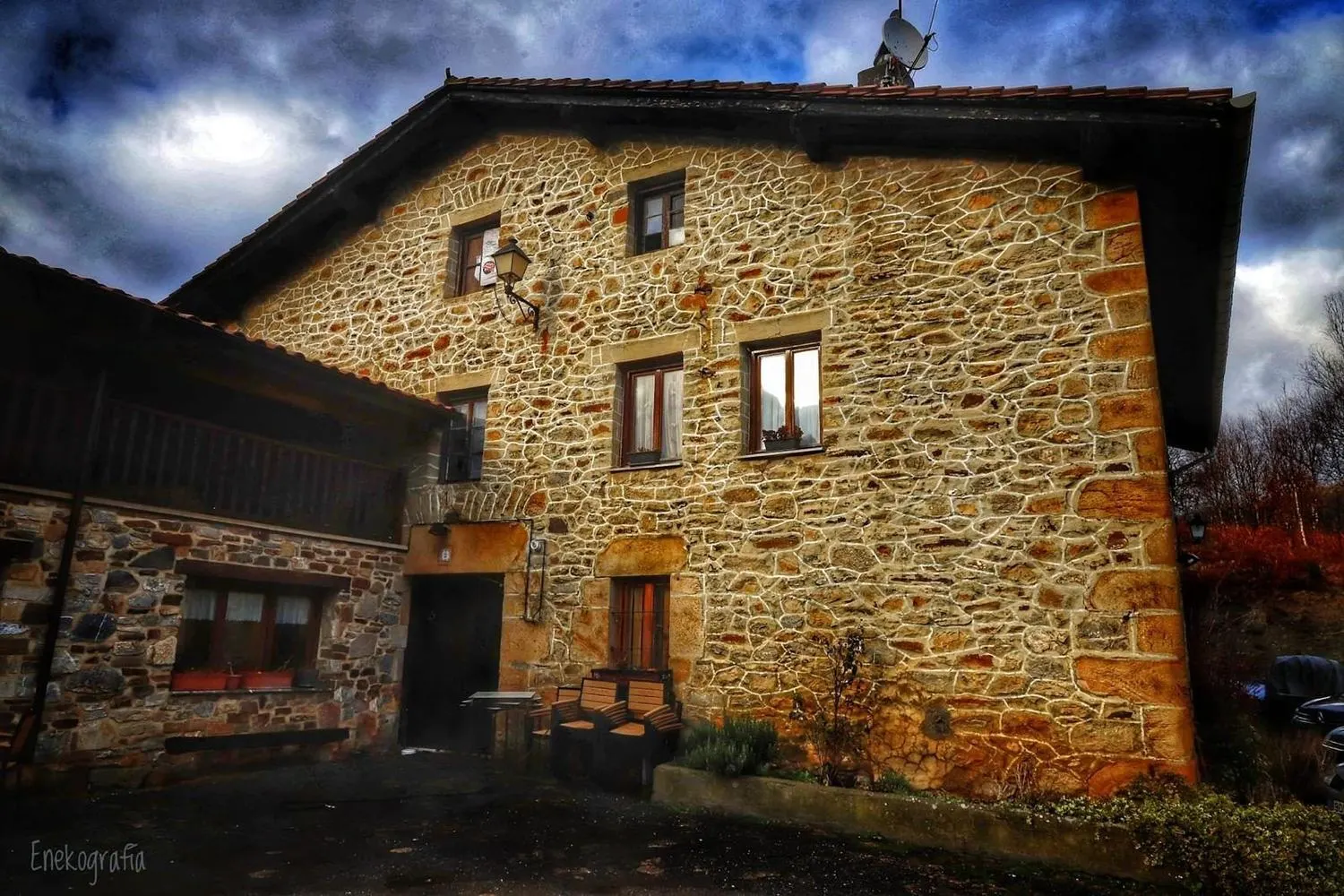 Fachada de piedra del caserío de la sidrería Iturrieta en Aramaio, bajo un cielo nublado