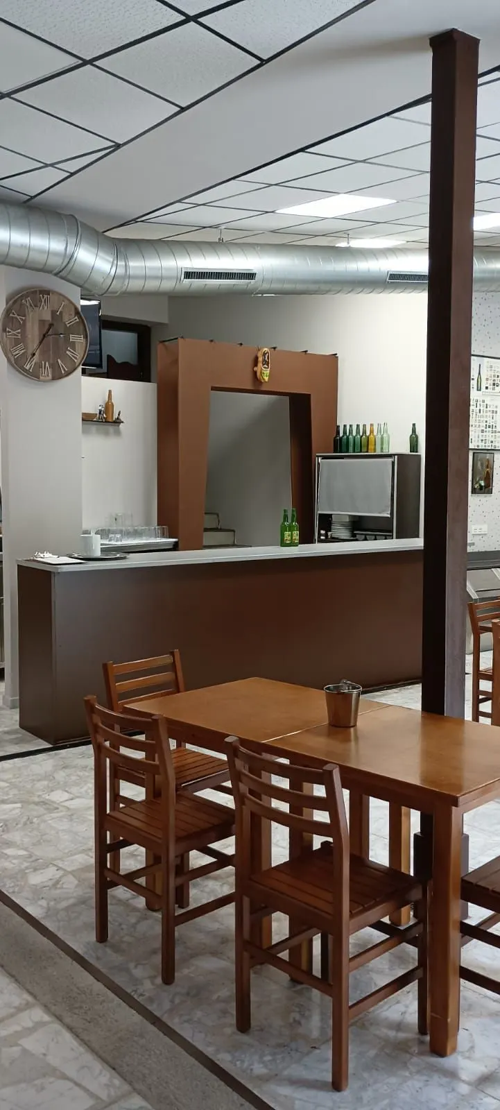 Barra del chigre con botellas de sidra y mesas de madera en primer plano