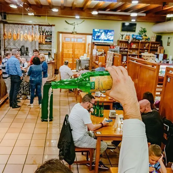Cider being poured from height in the cider bar with customers at the tables