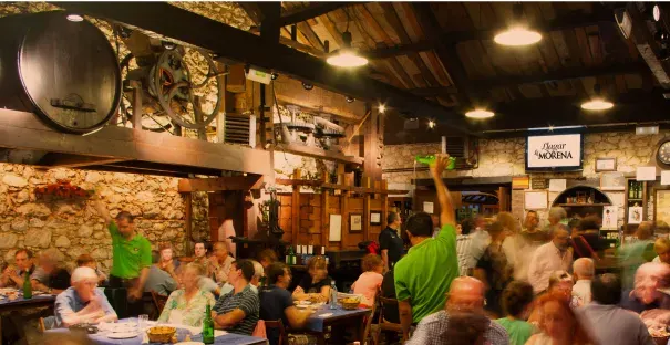 Salle à manger traditionnelle pleine de clients, avec un tonneau et des outils du cidre
