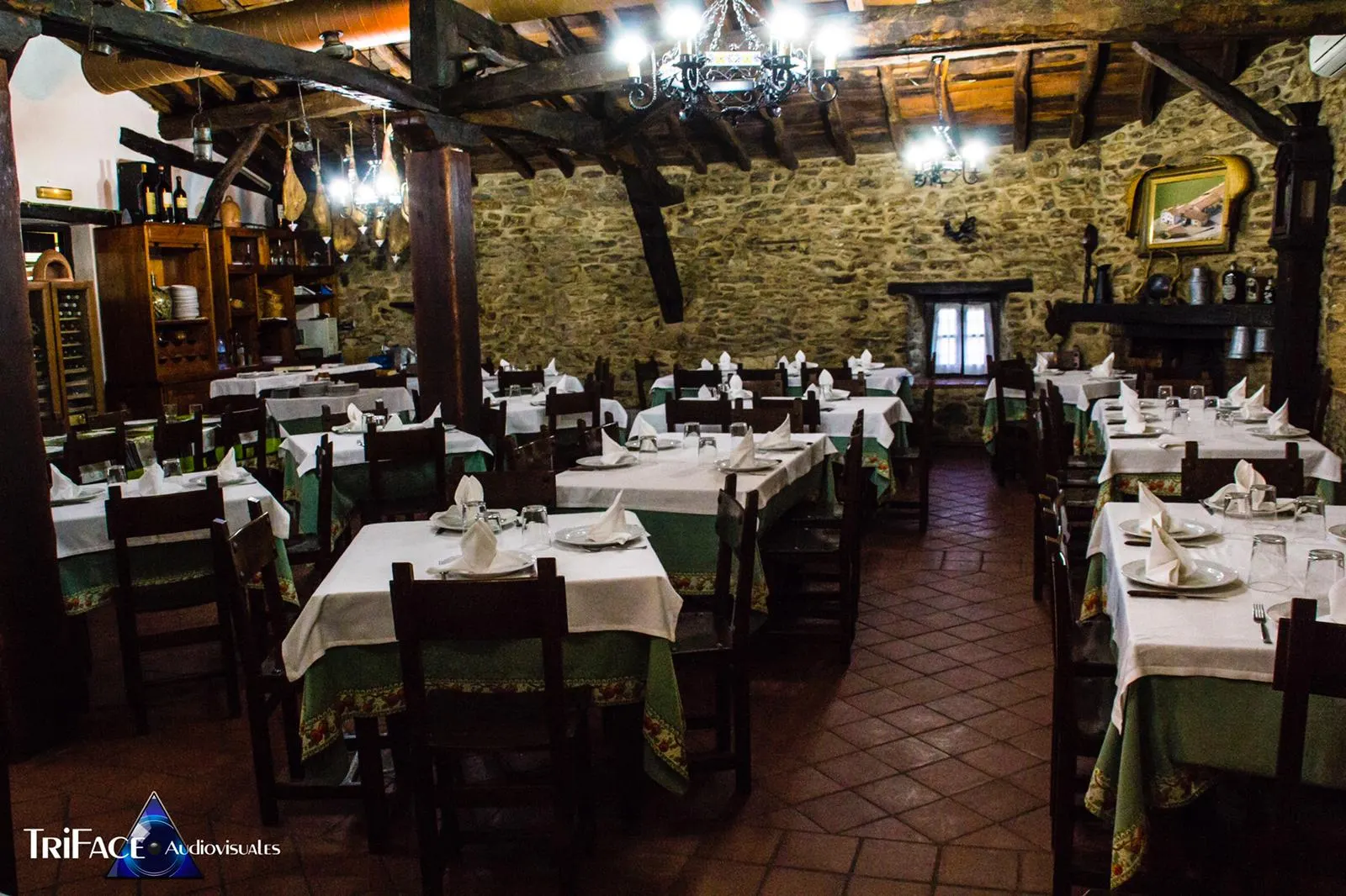 Comedor de la sidrería Mendiola, con muros de piedra, vigas de madera, lámparas de forja y mesas con mantel