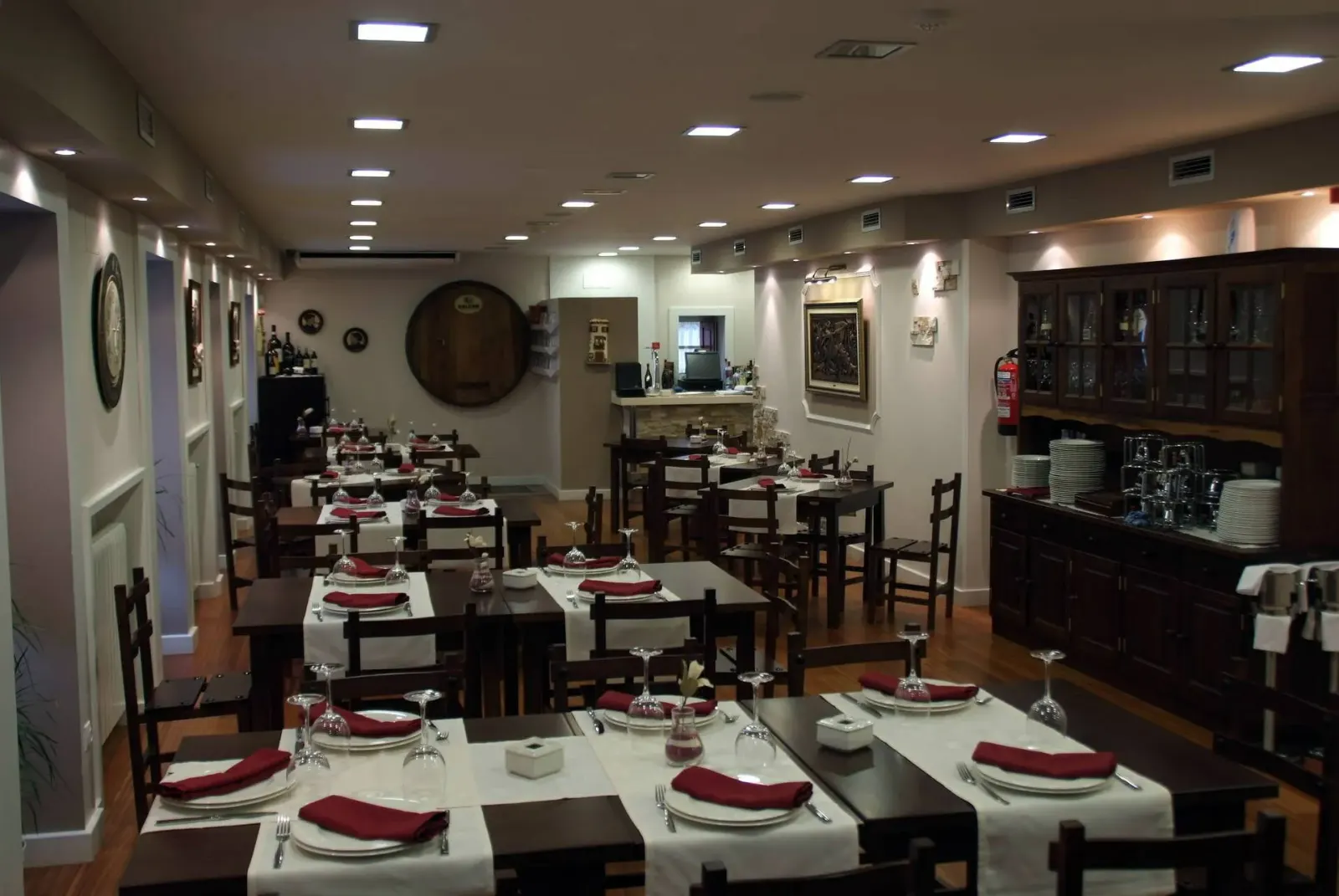 Comedor de la sidrería Donibane Batzoki, con mesas puestas con servilletas granates y la tapa de una barrica en la pared del fondo