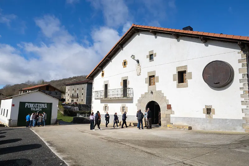 Caserío Perkatzenea en Madotz, con la bodega a la izquierda y un grupo de visita en la entrada