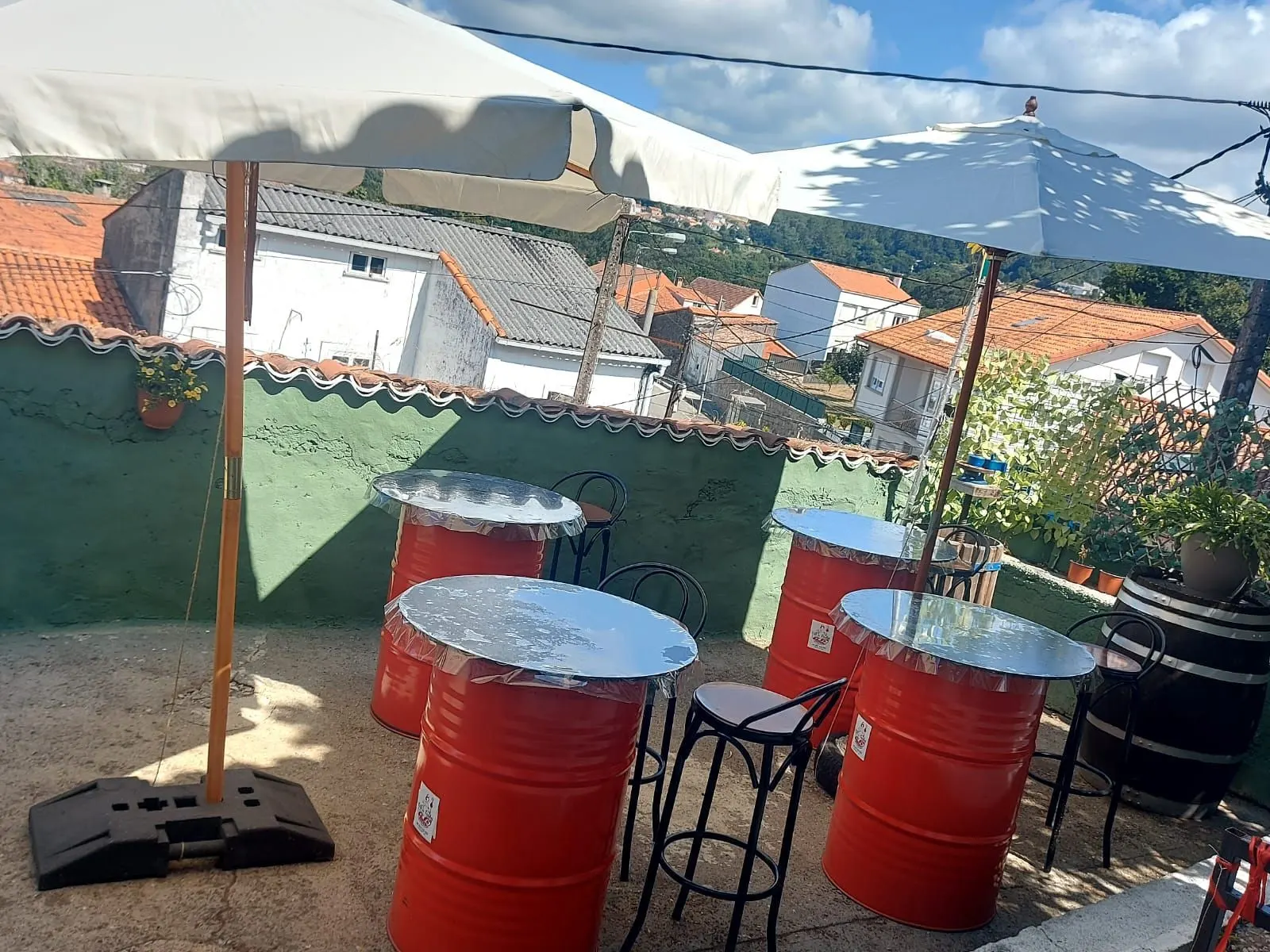 Terraza con mesas hechas con barriles y sombrillas