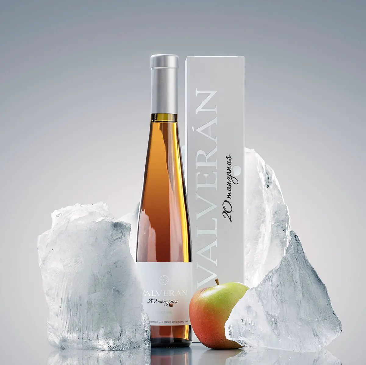 Botella y estuche de la sidra de hielo Valverán 20 Manzanas junto a bloques de hielo y una manzana